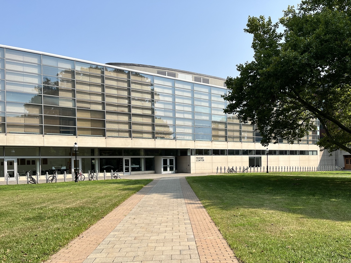 An exterior view of the Friend Center, a glass and stone building. A path leads through the courtyard to the main entrance.